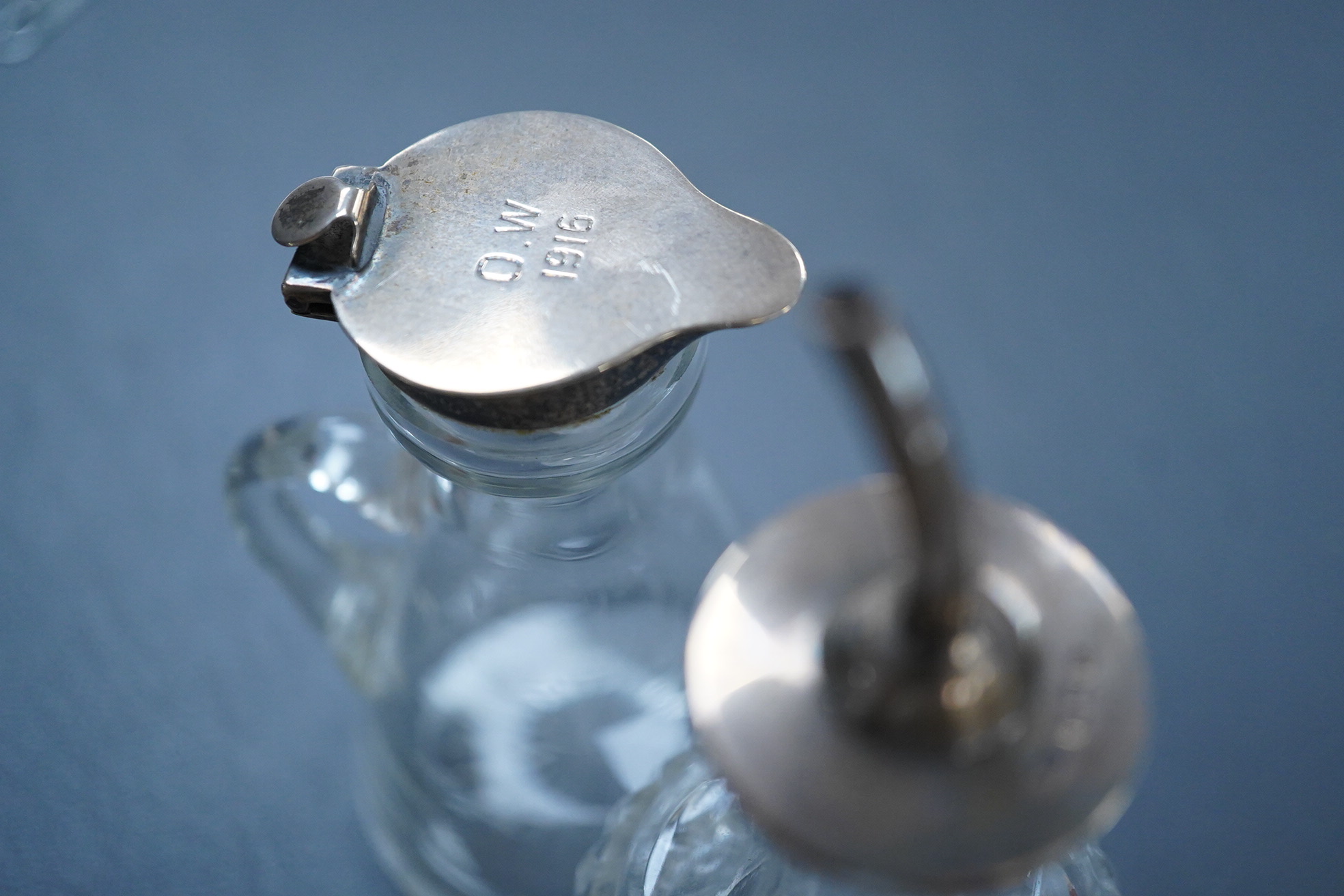 A George V silver mounted glass whisky noggin, indistinct maker's mark, Birmingham, 1913, with later engraved inscription, height 10.5cm, together with a later silver mounted cut glass oil or vinegar bottle.